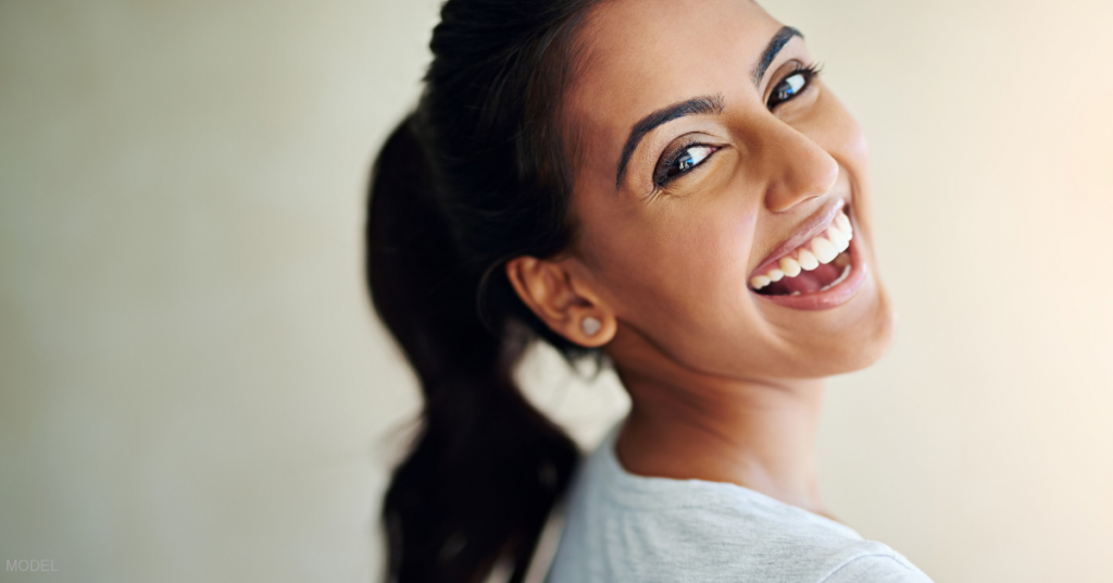 Smiling woman with pony tail looking back over her shoulder