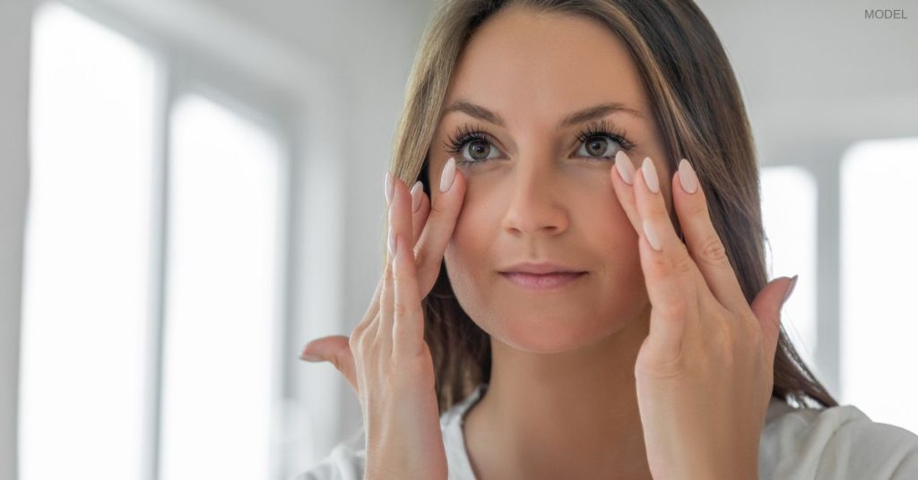 Woman with clear skin (model) holding hands up to her face.